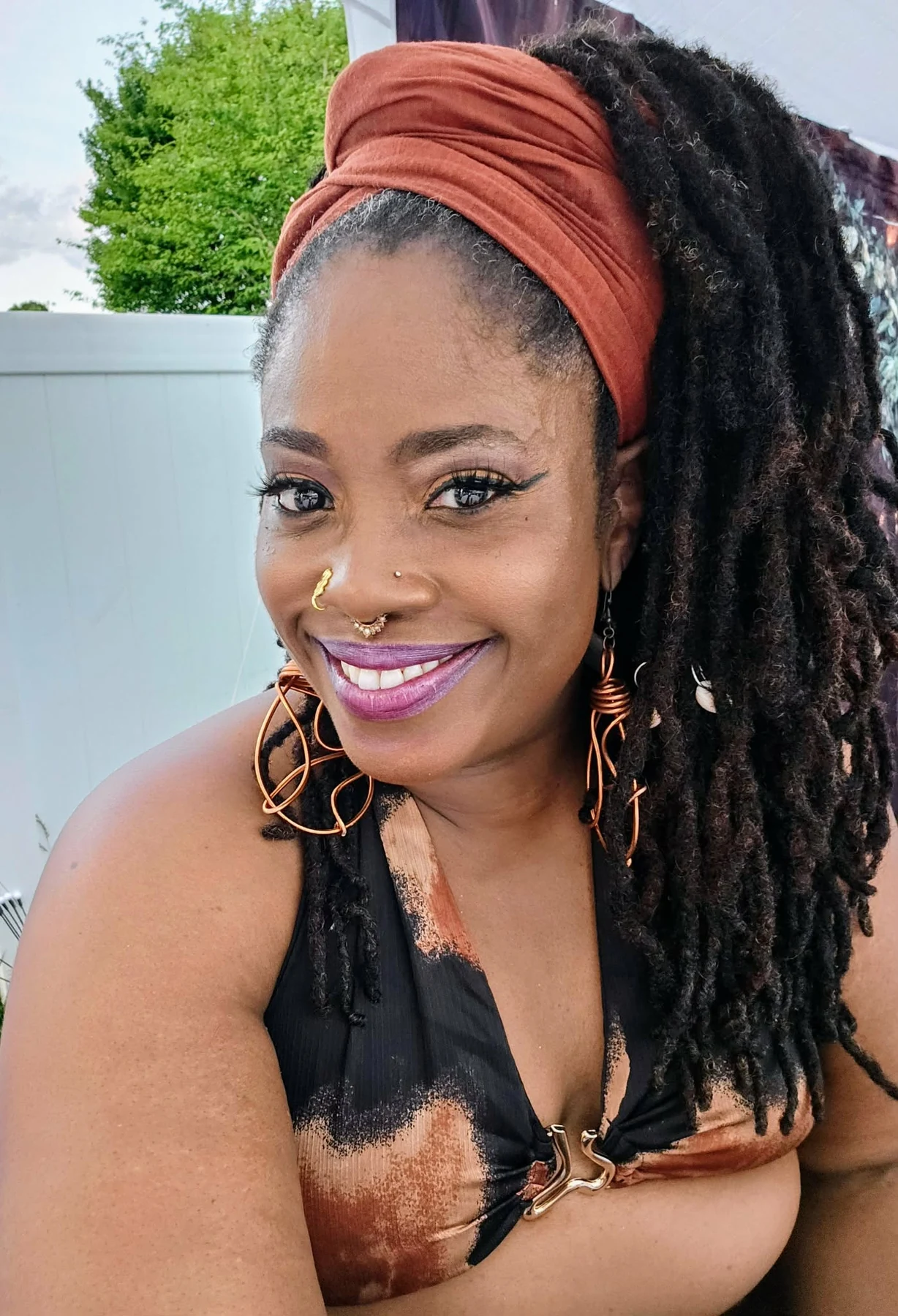 Crazy Carla smiling in a rust-colored headwrap